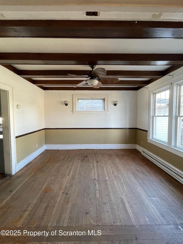 empty room featuring beamed ceiling, wood-type flooring, a ceiling fan, and baseboards