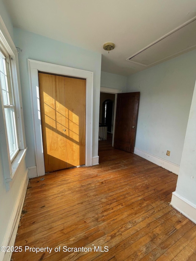 interior space featuring hardwood / wood-style flooring, attic access, and baseboards