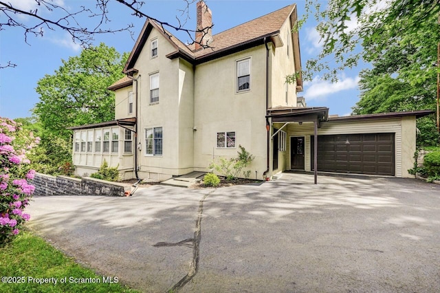 1614 Jefferson Ave, Dunmore, PA 18509 - view of front facade featuring stucco siding, an attached garage, asphalt driveway, and a chimney