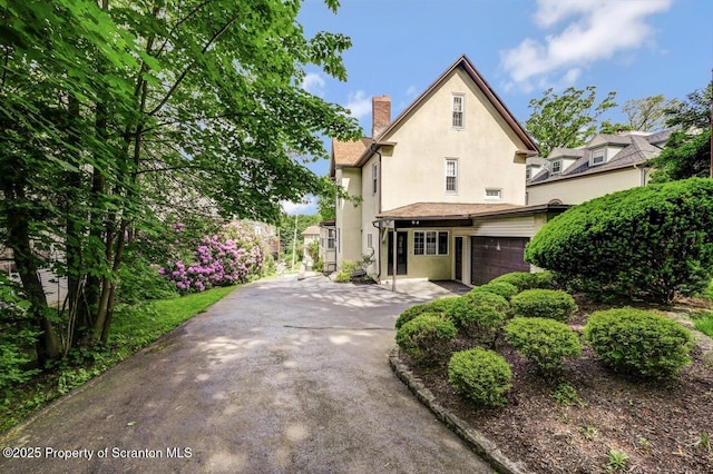 1614 Jefferson Ave, Dunmore, PA 18509 - view of front of home with stucco siding, a chimney, and an attached garage