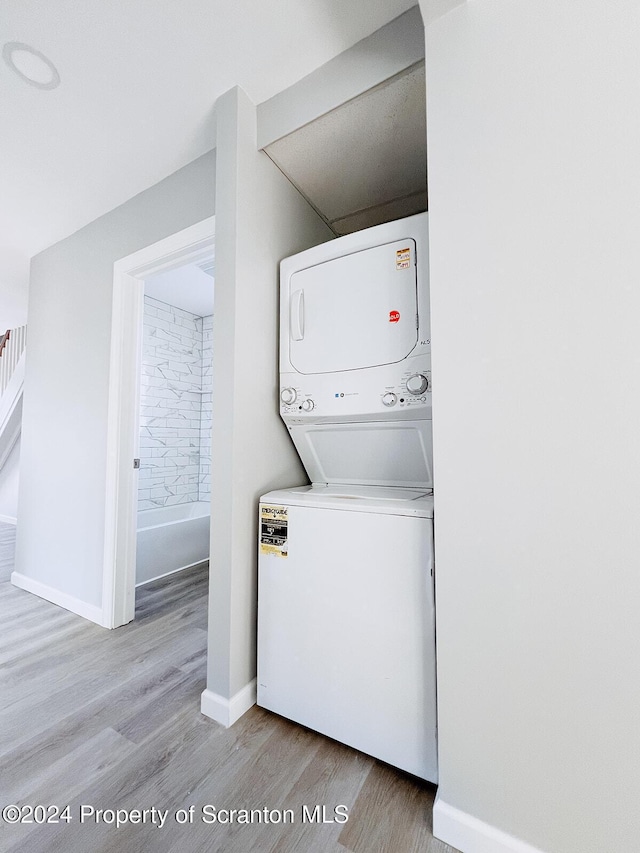 clothes washing area featuring light wood-type flooring and stacked washer and clothes dryer