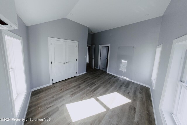 unfurnished bedroom featuring vaulted ceiling, wood-type flooring, and a closet