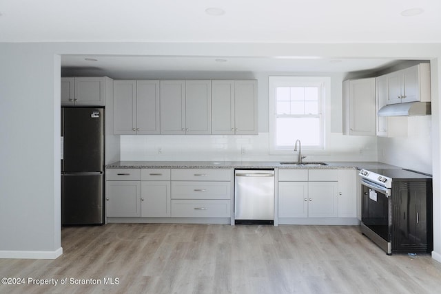 kitchen with sink, tasteful backsplash, light hardwood / wood-style flooring, white cabinets, and appliances with stainless steel finishes