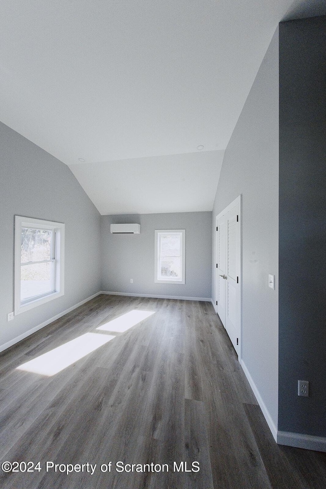 additional living space with lofted ceiling, a wealth of natural light, and a wall mounted AC