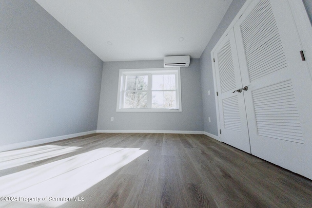 unfurnished bedroom with dark hardwood / wood-style floors and an AC wall unit