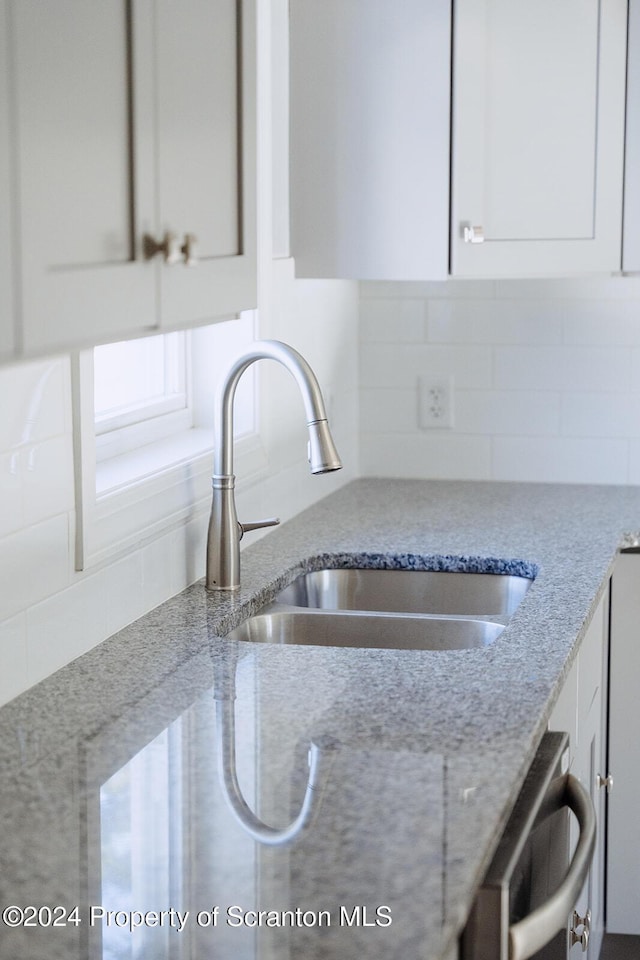 kitchen with white cabinets, tasteful backsplash, stainless steel dishwasher, and sink