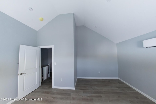 additional living space with vaulted ceiling, dark hardwood / wood-style floors, and a wall mounted air conditioner