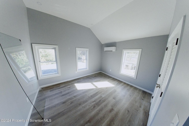 interior space with light hardwood / wood-style floors, a wall mounted AC, and lofted ceiling