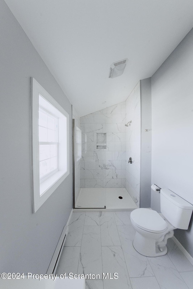 bathroom featuring a tile shower, baseboard heating, and toilet