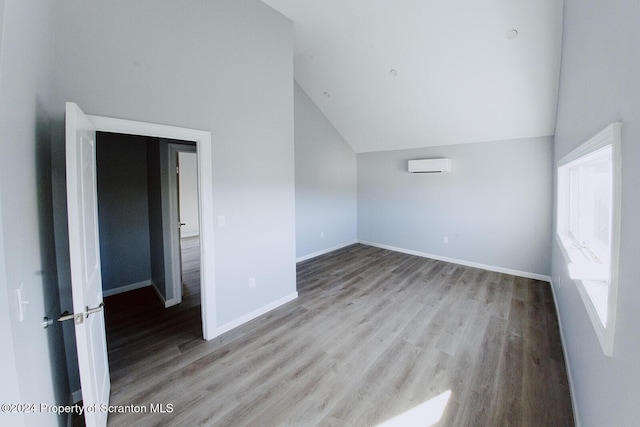 unfurnished room featuring vaulted ceiling, light hardwood / wood-style flooring, and a wall unit AC