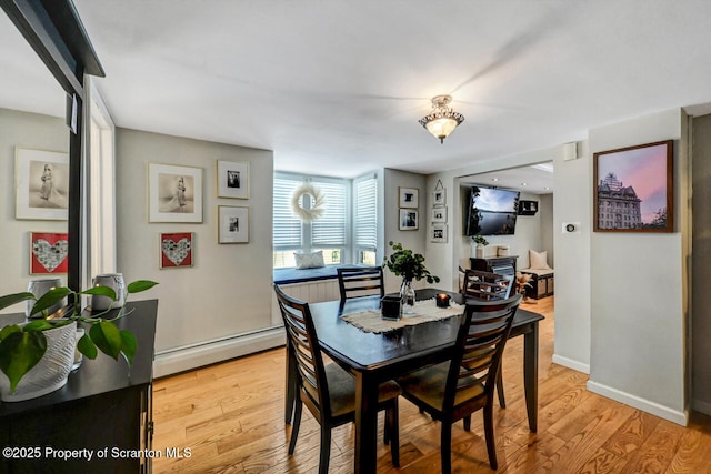 dining space with baseboard heating and light wood-type flooring