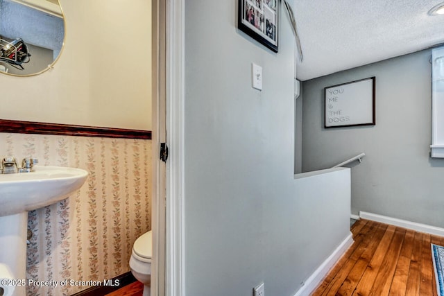 bathroom with hardwood / wood-style flooring, a textured ceiling, and toilet