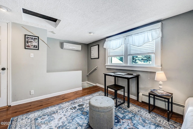 sitting room featuring wood-type flooring, a wall mounted AC, a textured ceiling, and a baseboard heating unit