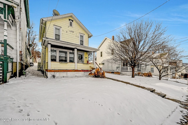 snow covered house featuring a porch