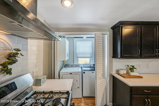 kitchen featuring backsplash, hardwood / wood-style floors, separate washer and dryer, island range hood, and gas stove