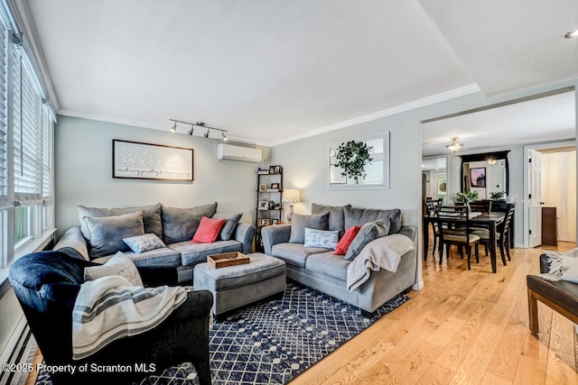 living room featuring crown molding, baseboard heating, a wall unit AC, rail lighting, and light hardwood / wood-style floors