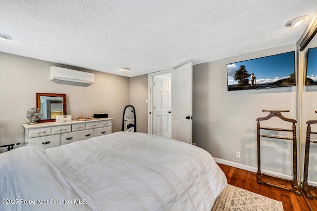 bedroom with a wall mounted air conditioner, dark hardwood / wood-style floors, and a textured ceiling