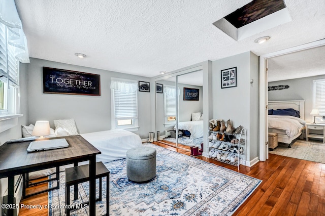 bedroom with a textured ceiling, a closet, and dark hardwood / wood-style flooring