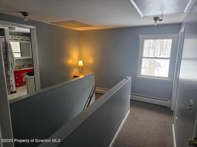 corridor featuring a baseboard heating unit, sink, and carpet flooring