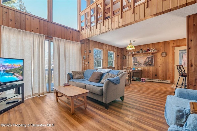 living room with hardwood / wood-style floors, wood walls, and baseboard heating