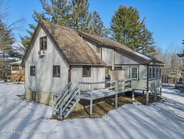 snow covered back of property with cooling unit and a deck