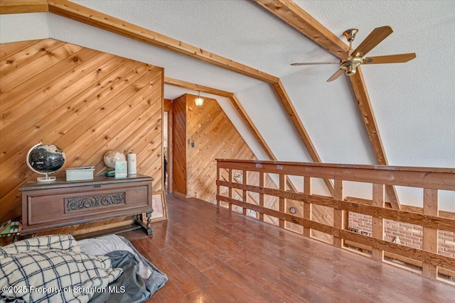 additional living space with dark wood-type flooring, vaulted ceiling with beams, a textured ceiling, and wooden walls