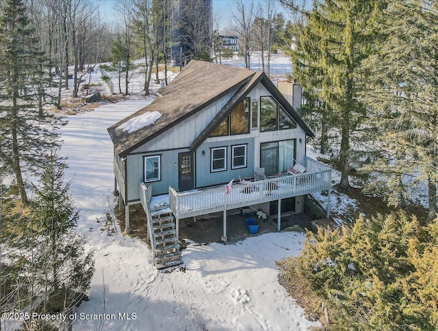 snow covered back of property featuring a deck