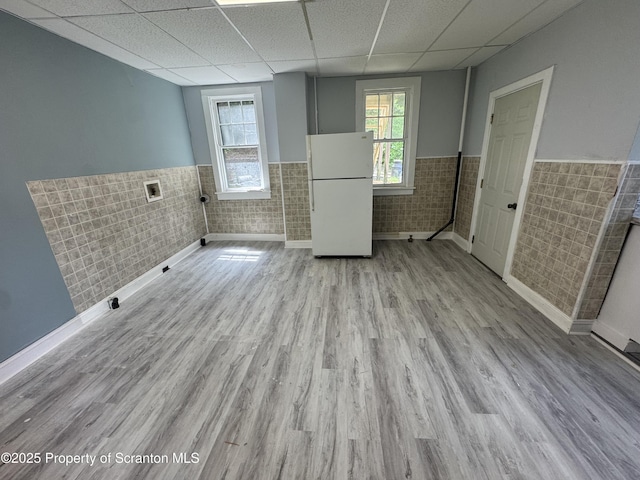 clothes washing area with wainscoting, tile walls, and wood finished floors