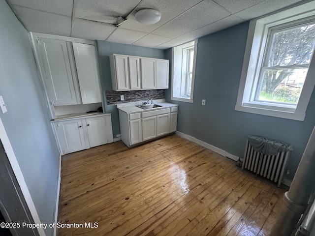 washroom with radiator heating unit, a sink, light wood-type flooring, and baseboards