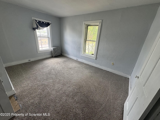 carpeted empty room with radiator, healthy amount of natural light, and baseboards