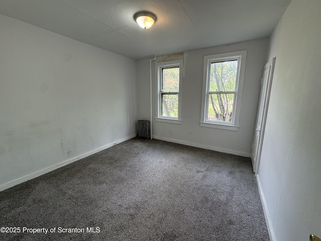 spare room with radiator heating unit, carpet flooring, and baseboards