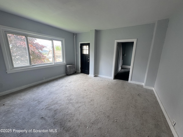 unfurnished bedroom with radiator heating unit, carpet floors, and baseboards