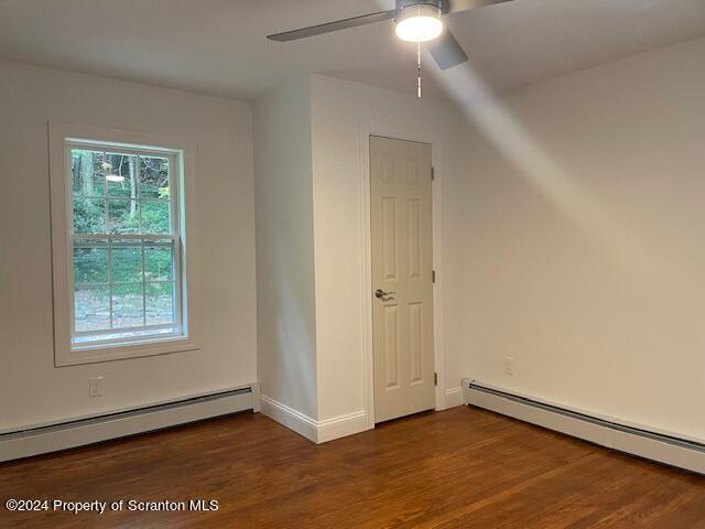 bonus room featuring dark hardwood / wood-style flooring, ceiling fan, and a baseboard heating unit