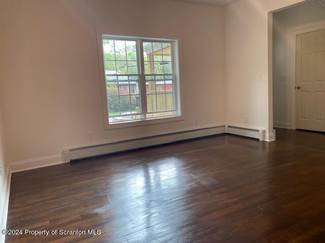 unfurnished room featuring dark wood-type flooring and a baseboard radiator