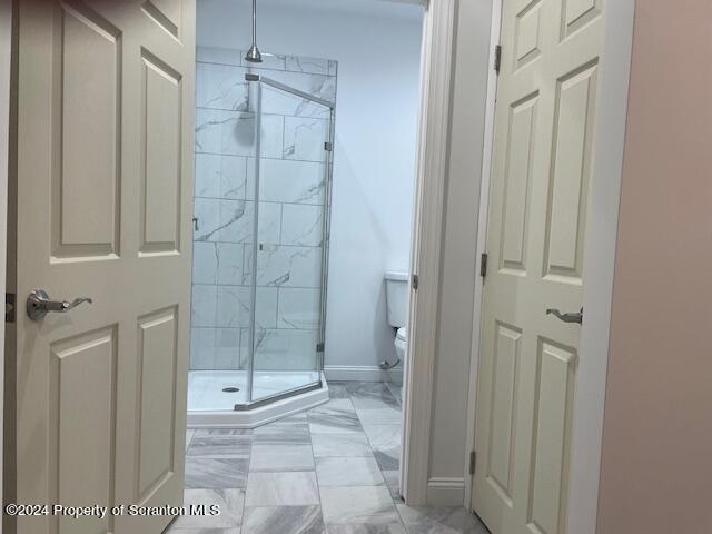 bathroom with toilet and an enclosed shower