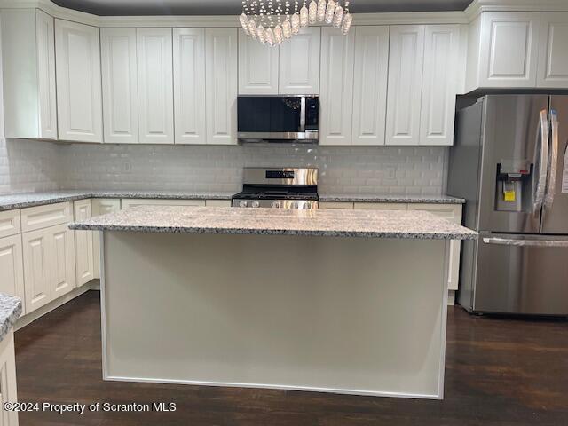 kitchen with white cabinets, a center island, light stone countertops, and appliances with stainless steel finishes