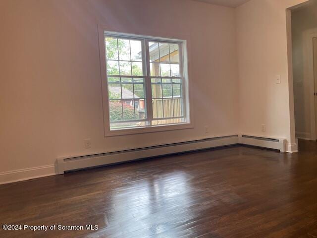 empty room with dark hardwood / wood-style flooring and baseboard heating