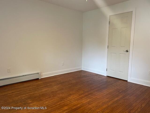 empty room with dark hardwood / wood-style floors and baseboard heating