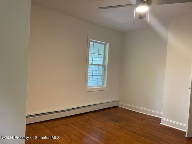 empty room featuring dark hardwood / wood-style floors, ceiling fan, and baseboard heating