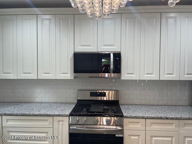 kitchen with white cabinets, decorative backsplash, and stainless steel appliances