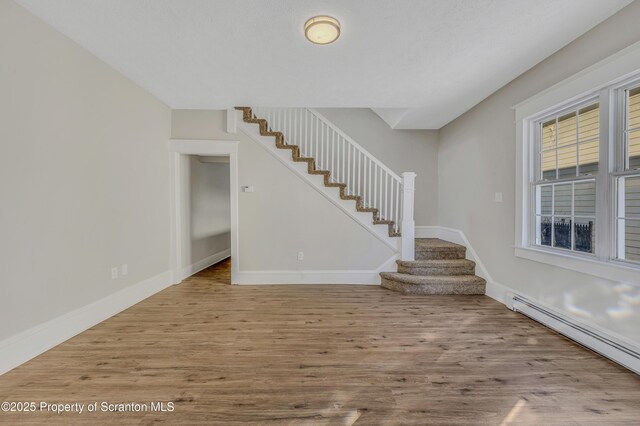 stairs with a baseboard heating unit, a textured ceiling, and hardwood / wood-style floors