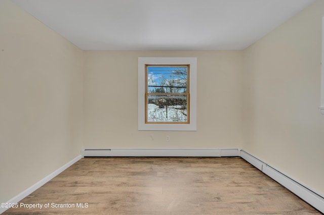 empty room with light wood-type flooring and a baseboard heating unit