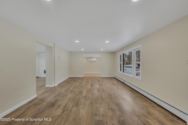 unfurnished room featuring light wood-type flooring, a wall unit AC, and a baseboard radiator