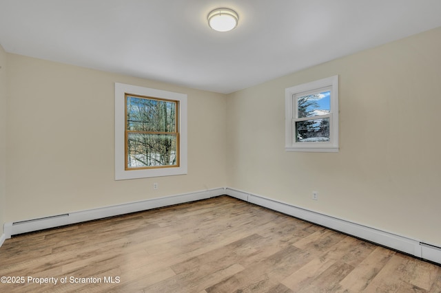 empty room featuring light hardwood / wood-style floors, a baseboard radiator, and a healthy amount of sunlight