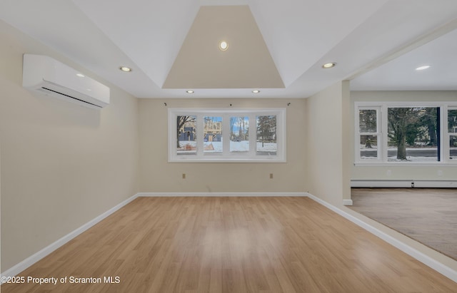 unfurnished living room with a raised ceiling, light hardwood / wood-style flooring, baseboard heating, and a wall mounted air conditioner