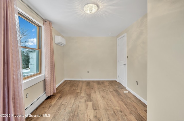 empty room featuring a wall mounted AC, a baseboard heating unit, and light hardwood / wood-style flooring