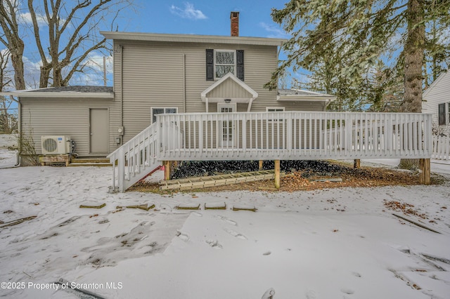 snow covered rear of property with a wooden deck and ac unit