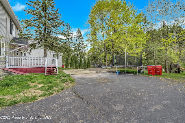 view of yard with a deck and a trampoline