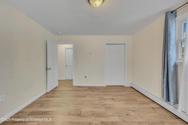 unfurnished bedroom with light hardwood / wood-style floors and a baseboard heating unit