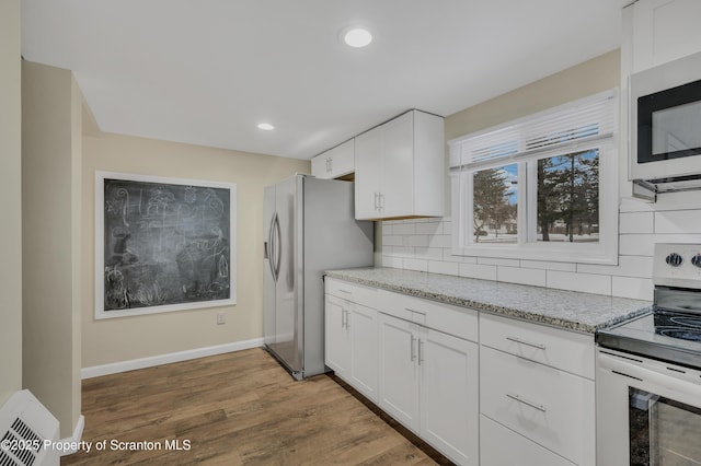 kitchen with appliances with stainless steel finishes, white cabinetry, and tasteful backsplash